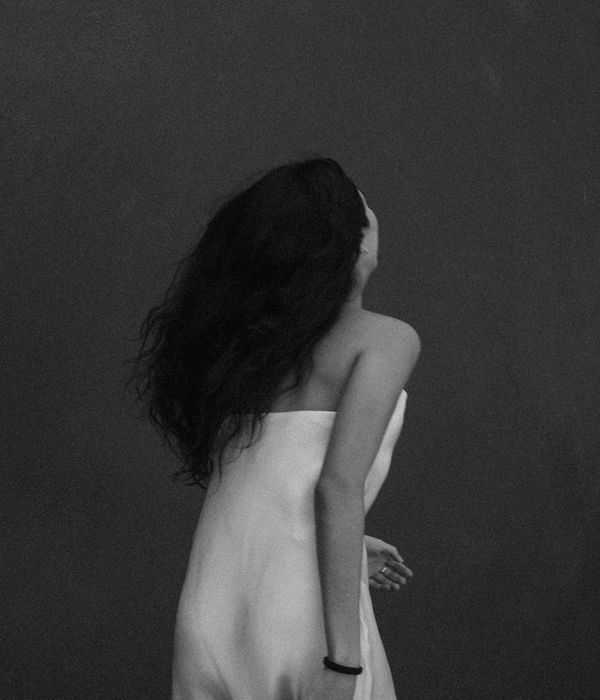 Woman with a serene expression performing a gentle cardio movement in a minimalist room.